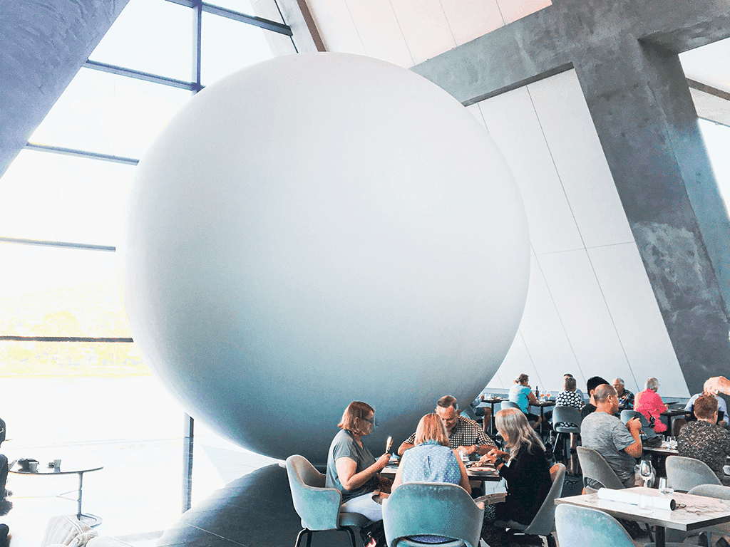 Image shows a giant spherical art installation in MONA Museum in Tasmania above the words "8 Travel Spends You'll Never Regret"