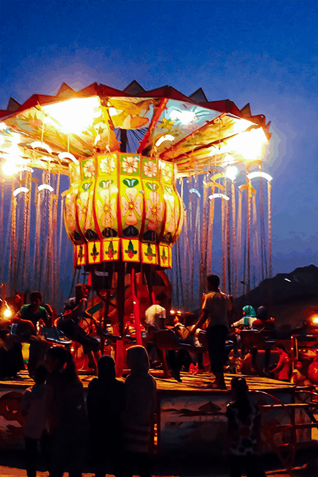 Image shows a brightly lit carnival ride full of Egyptian carnivalgoers.