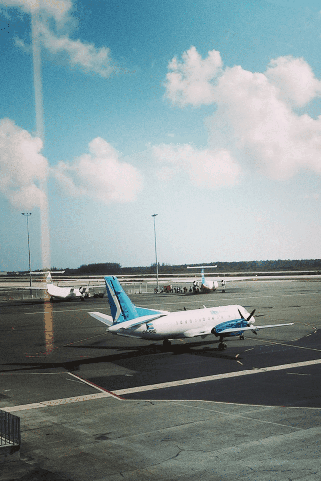 Image shows a plane preparing for takeoff against a bright blue sky. The plane's tail is bright blue and matches the sky.