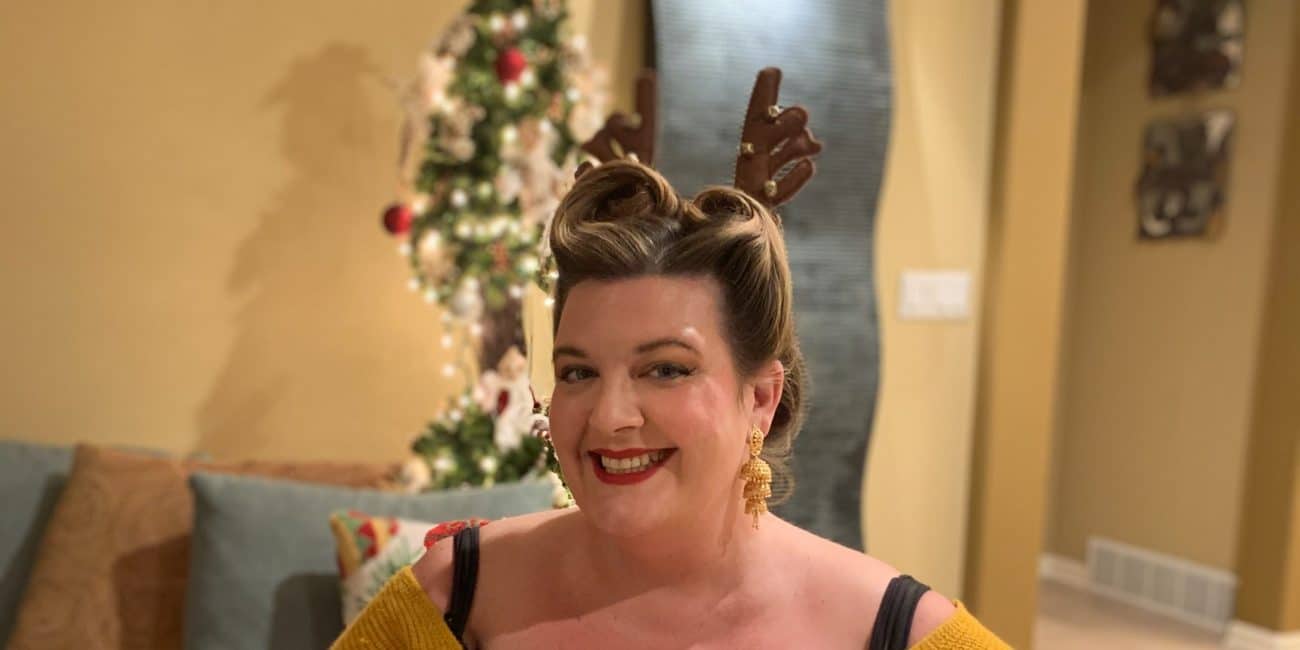 Jezebel is smiling into the camera wearing reindeer ears.